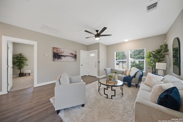 living room with baseboards, visible vents, dark wood finished floors, and a ceiling fan