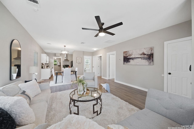 living room with a ceiling fan, visible vents, light wood-style flooring, and baseboards