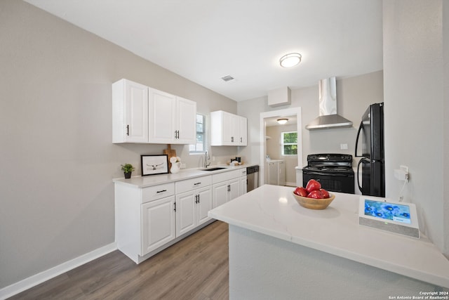 kitchen with white cabinetry, wall chimney range hood, black appliances, light hardwood / wood-style floors, and washer and clothes dryer