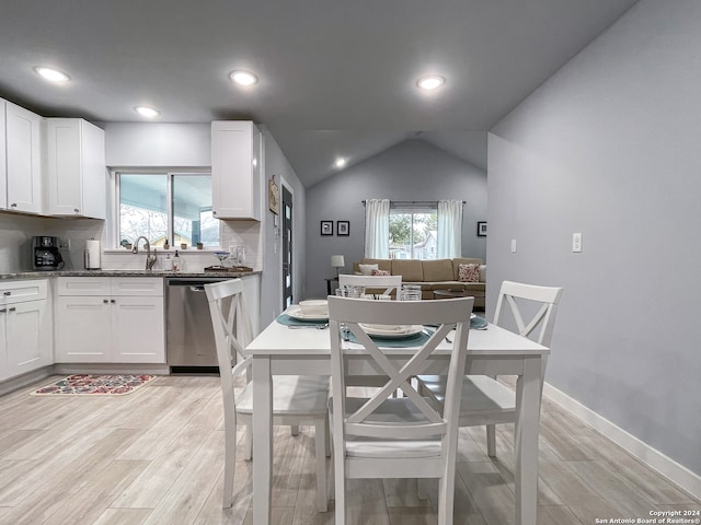 dining room featuring vaulted ceiling, sink, and light wood-type flooring