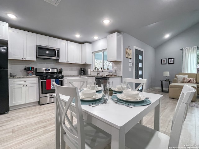 kitchen with white cabinetry, vaulted ceiling, light hardwood / wood-style flooring, and appliances with stainless steel finishes