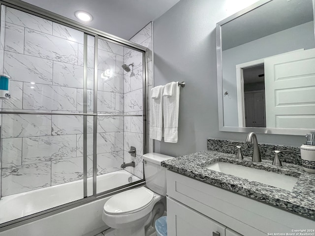 full bathroom featuring toilet, shower / bath combination with glass door, and vanity