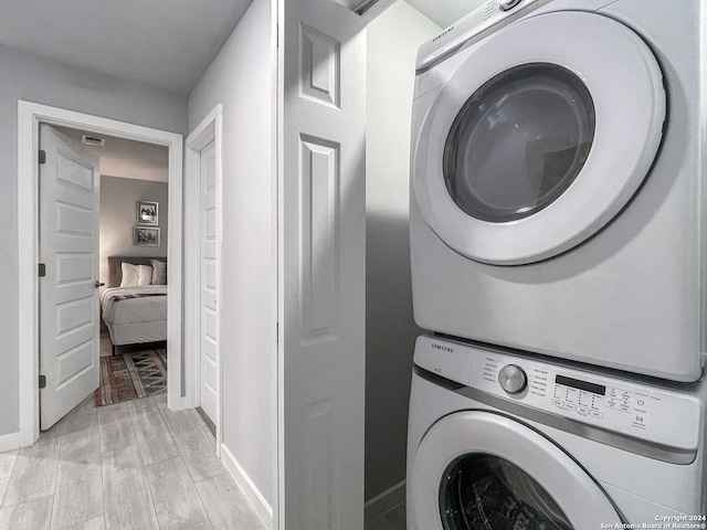 washroom with light hardwood / wood-style floors and stacked washer / drying machine