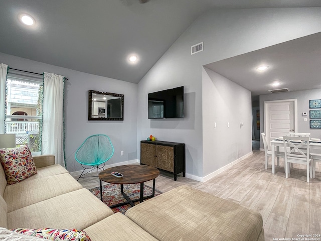 living room with light hardwood / wood-style floors and high vaulted ceiling