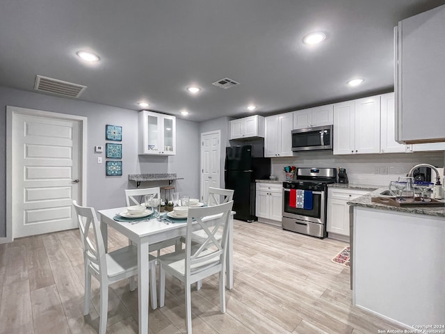 kitchen with sink, appliances with stainless steel finishes, light wood-type flooring, and light stone counters