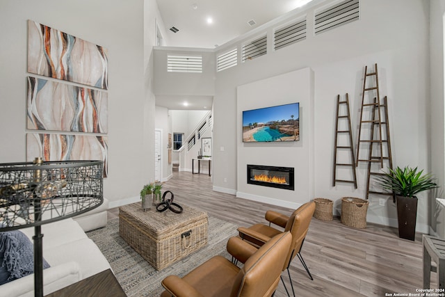 living room featuring light wood-type flooring and a high ceiling