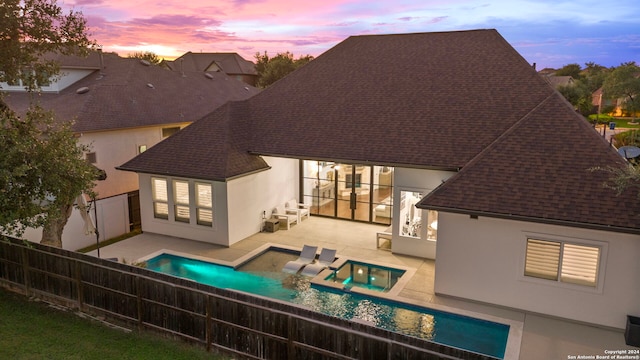 back house at dusk featuring a fenced in pool and a patio area