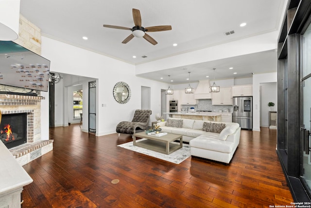 living room with crown molding, ceiling fan, dark hardwood / wood-style flooring, and a brick fireplace