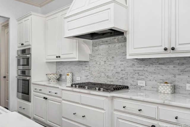 kitchen featuring backsplash, stainless steel appliances, custom range hood, and white cabinets