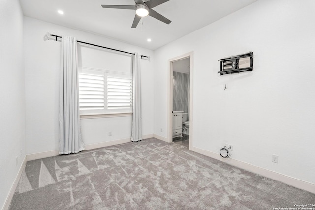 unfurnished bedroom featuring ensuite bathroom, light colored carpet, and ceiling fan