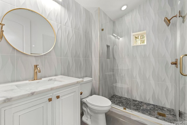 bathroom featuring toilet, tile walls, vanity, a shower with door, and backsplash