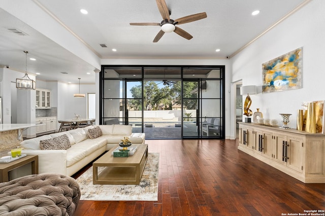 living room with ornamental molding, dark wood-type flooring, and ceiling fan