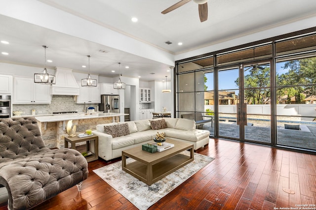 living room with crown molding, dark wood-type flooring, and ceiling fan