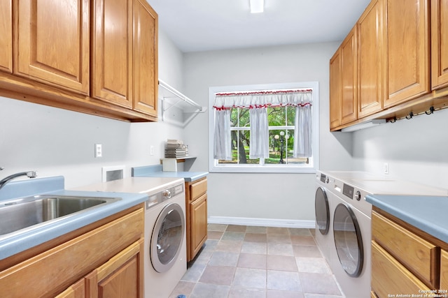 washroom with light tile patterned flooring, sink, washing machine and dryer, and cabinets