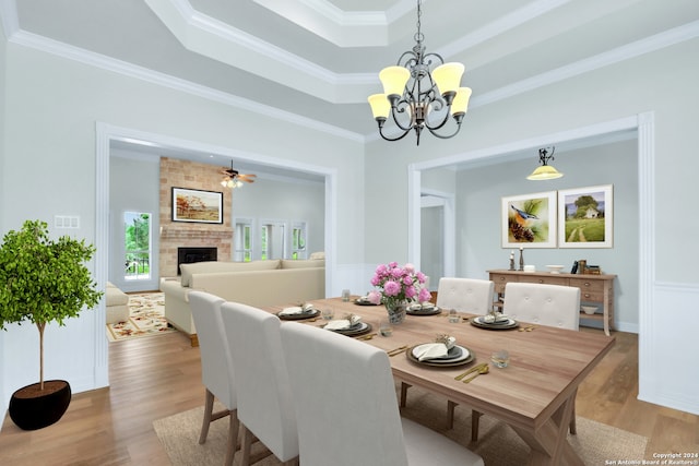 dining room featuring a tray ceiling, hardwood / wood-style floors, ornamental molding, brick wall, and a brick fireplace