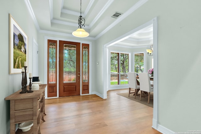 foyer entrance with light hardwood / wood-style floors, ornamental molding, and a tray ceiling