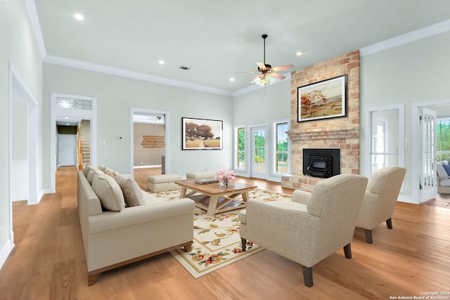 living room featuring ceiling fan, brick wall, light hardwood / wood-style flooring, and a brick fireplace