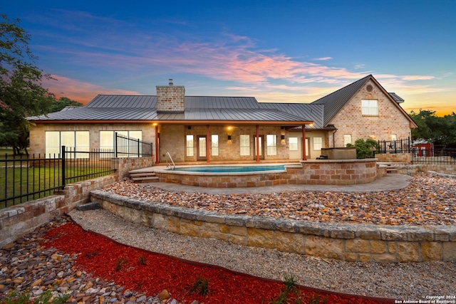 back house at dusk featuring a jacuzzi