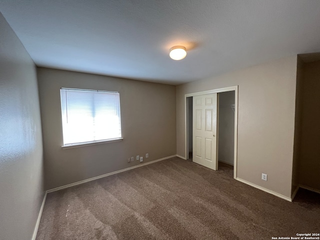 unfurnished bedroom featuring dark colored carpet and a closet