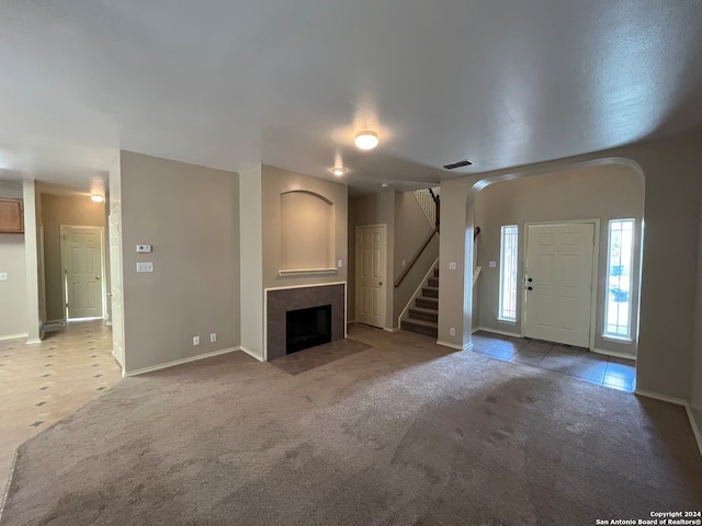 unfurnished living room featuring carpet flooring and a tiled fireplace