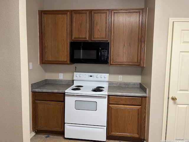 kitchen featuring white range with electric stovetop, black microwave, brown cabinets, and dark countertops