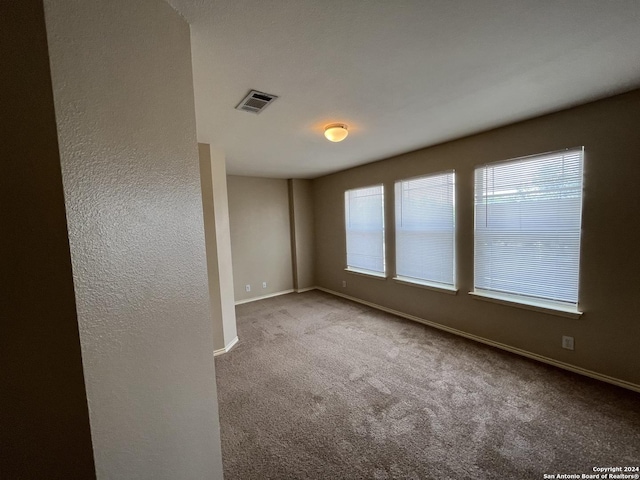 spare room featuring light carpet, baseboards, and visible vents