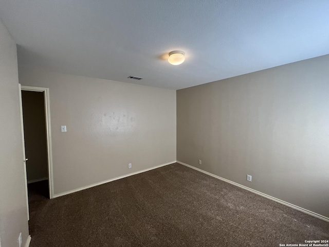 unfurnished room with baseboards, visible vents, and dark colored carpet