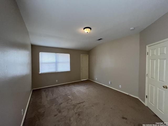 unfurnished room featuring dark colored carpet, visible vents, and baseboards