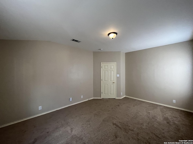 spare room featuring dark colored carpet, visible vents, and baseboards