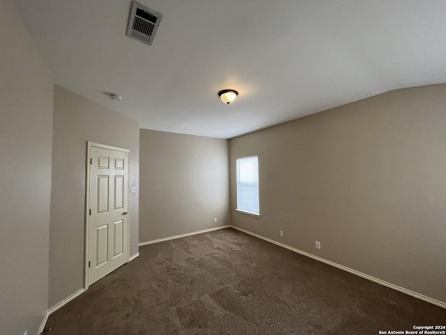 spare room featuring dark colored carpet, visible vents, and baseboards