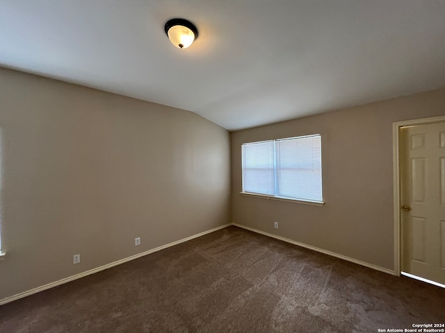 empty room featuring lofted ceiling and dark carpet