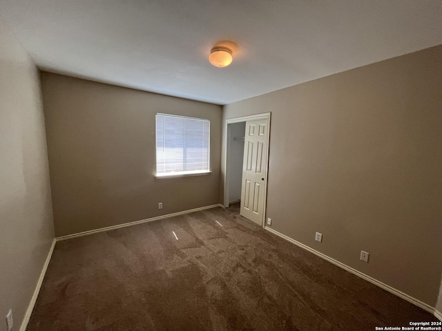 unfurnished bedroom featuring a closet, dark carpet, and baseboards