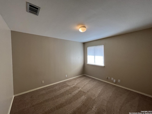 unfurnished room featuring carpet, visible vents, and baseboards