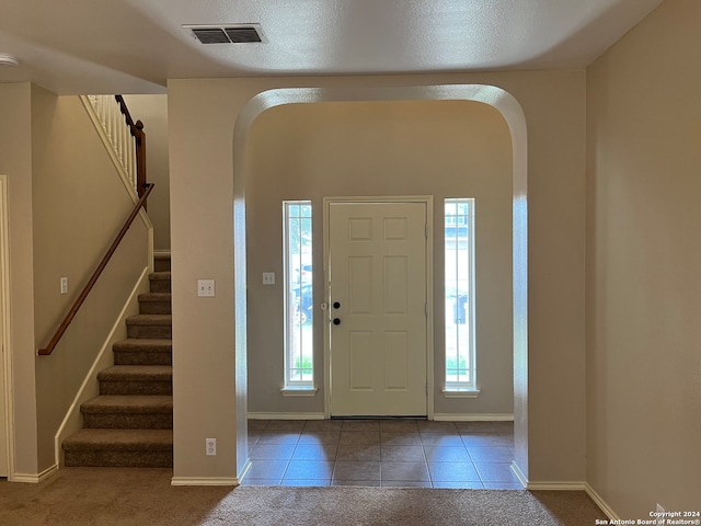 carpeted foyer entrance featuring a textured ceiling