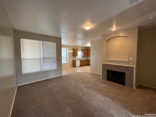 unfurnished living room with a tiled fireplace and light colored carpet