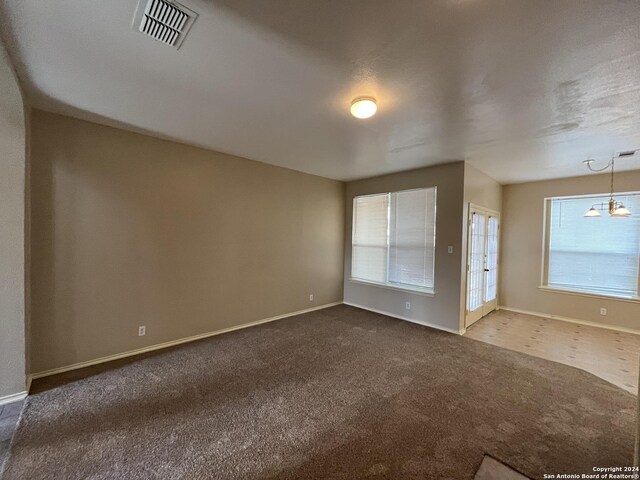 carpeted empty room featuring a notable chandelier