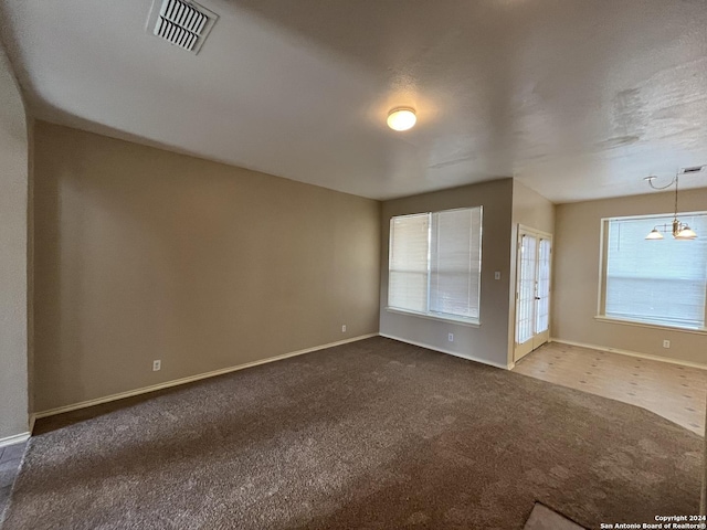 spare room with carpet floors, baseboards, and visible vents