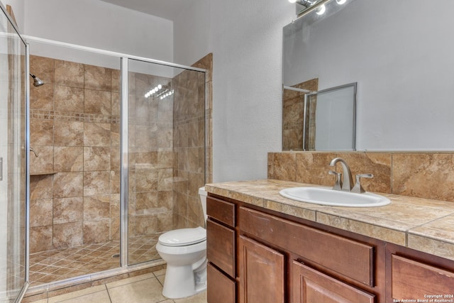 bathroom featuring backsplash, tile patterned flooring, vanity, an enclosed shower, and toilet