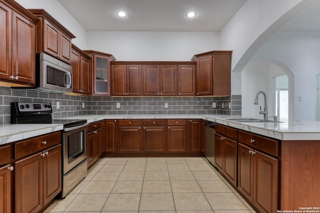 kitchen with appliances with stainless steel finishes, sink, backsplash, light tile patterned floors, and kitchen peninsula