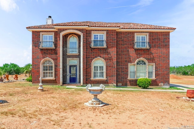 view of front of house featuring a tiled roof, brick siding, and a front yard