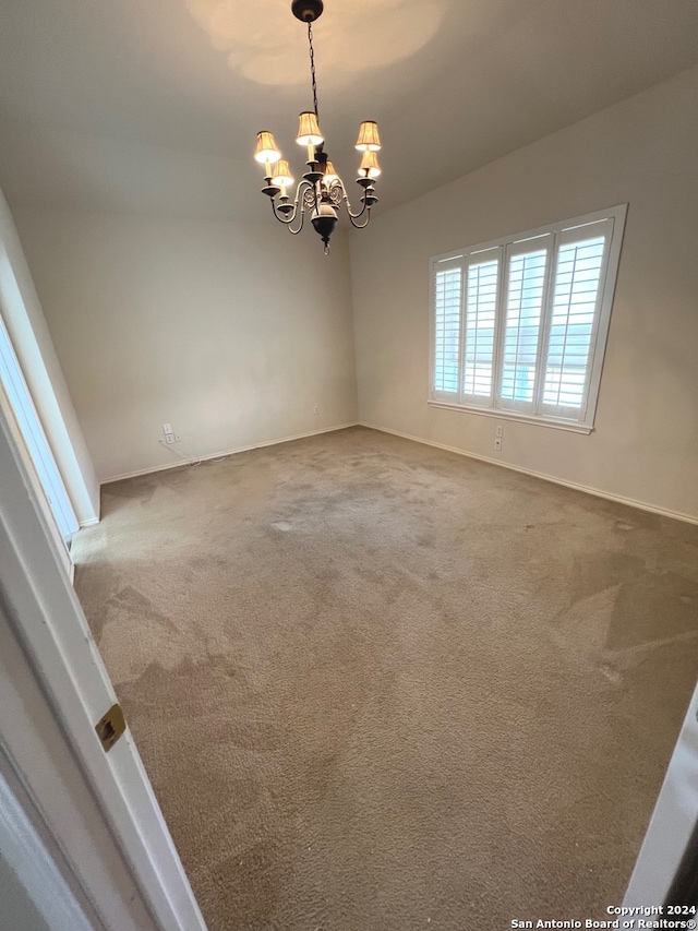 unfurnished room with carpet floors and a chandelier