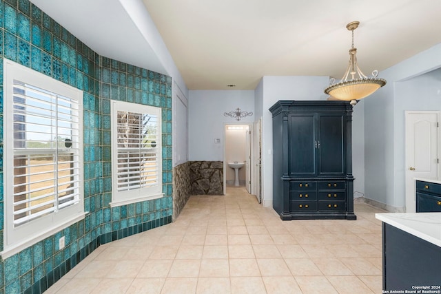 interior space featuring tile patterned flooring, a sink, and baseboards