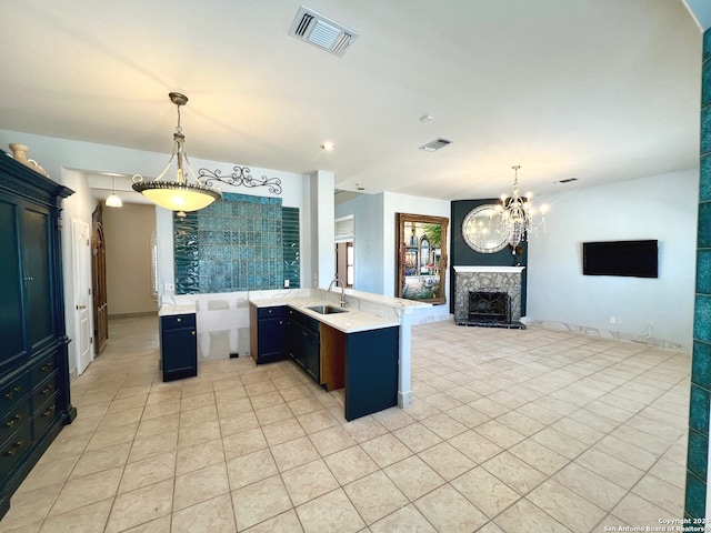 kitchen featuring sink, a notable chandelier, kitchen peninsula, a premium fireplace, and light tile patterned floors