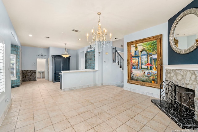 kitchen with a fireplace with raised hearth, baseboards, visible vents, and a notable chandelier