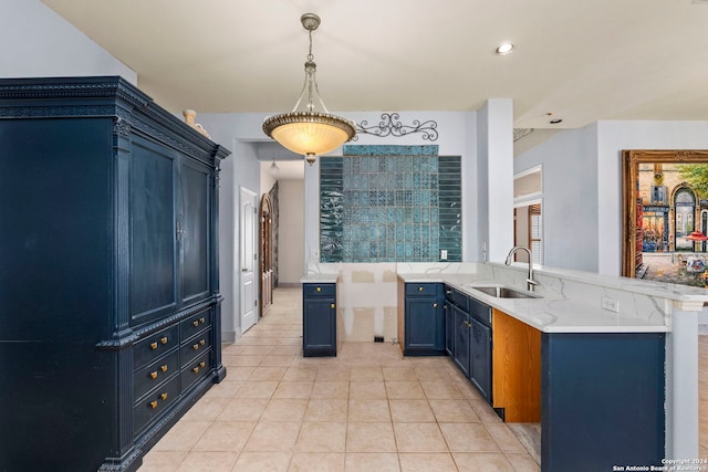 kitchen with light stone counters, light tile patterned floors, a sink, blue cabinets, and a peninsula