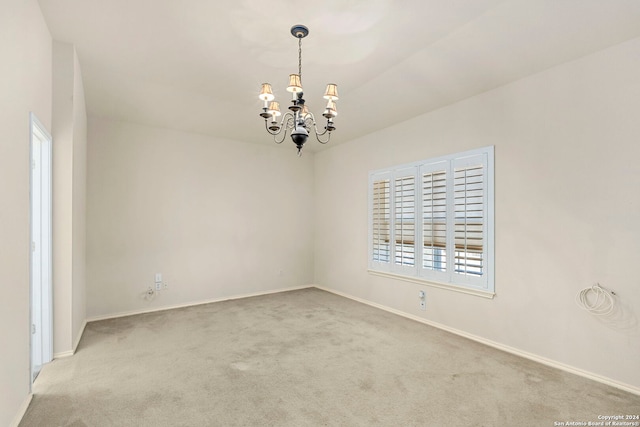 unfurnished room featuring a chandelier, light colored carpet, and baseboards