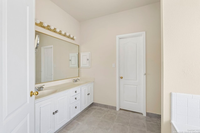 full bath with double vanity, baseboards, and a sink