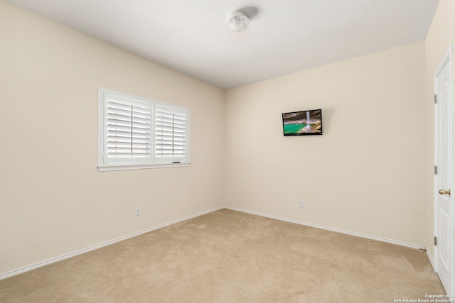 spare room featuring baseboards and light colored carpet