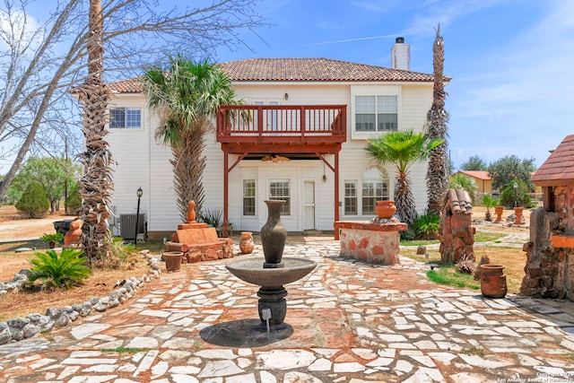 back of house with a patio, a chimney, a balcony, cooling unit, and a tiled roof