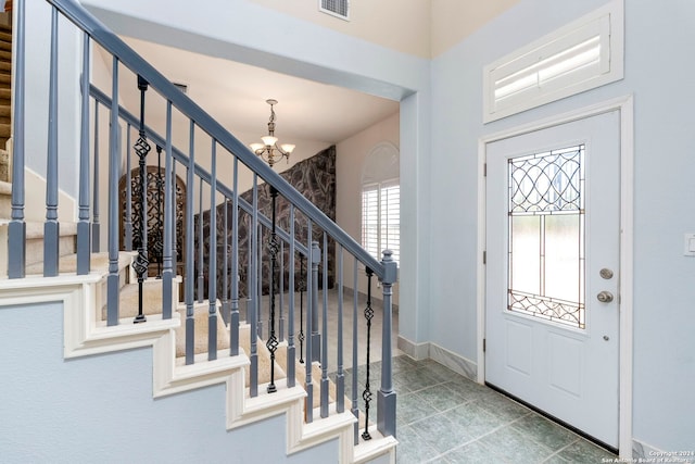 foyer entrance featuring visible vents, a notable chandelier, stairway, and baseboards